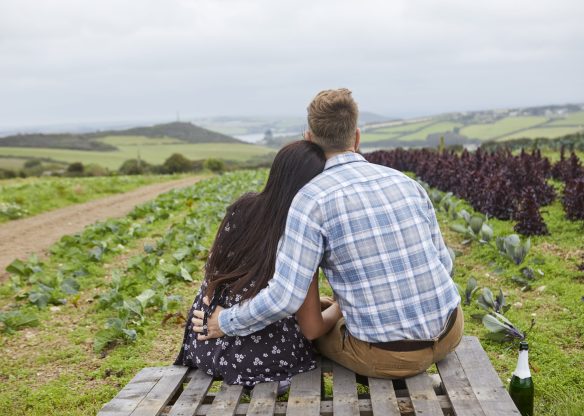 Couple in rural location sitting on pallets looking away